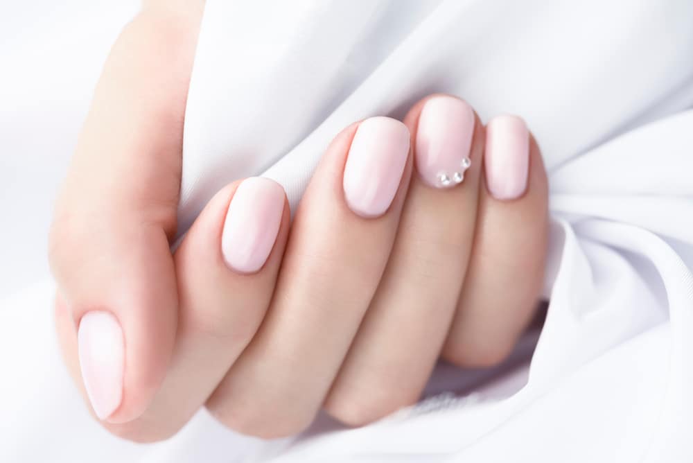 Beige manicure with pearls on a white background