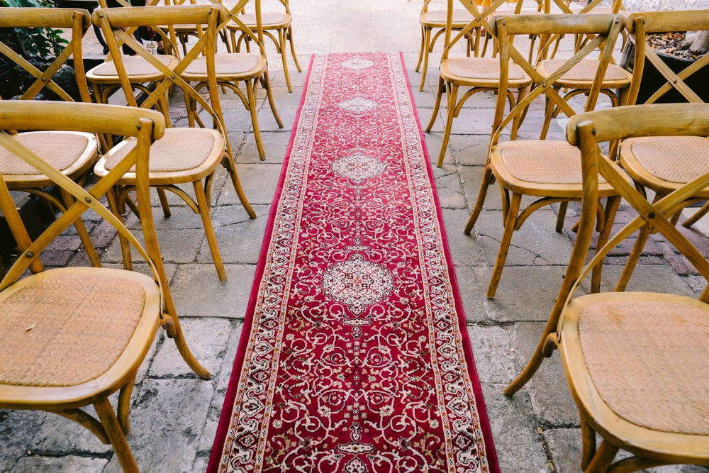 Bohemian wedding ceremony decor with red turkish rug as the aisle and oak cross back chairs