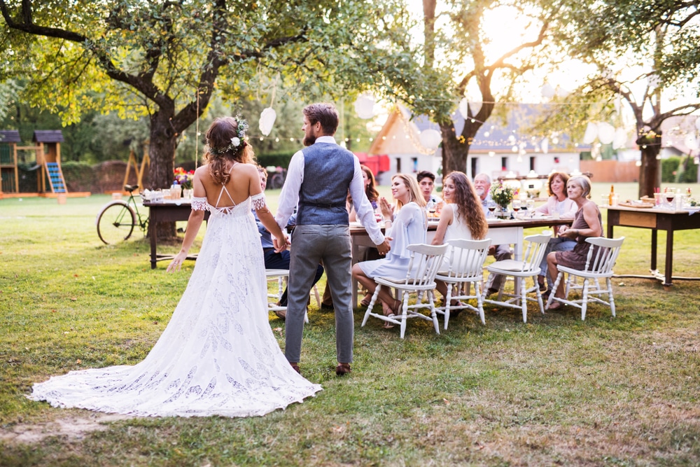 Bride And Groom Holding Hands At Wedding Reception Outside In the Backyard