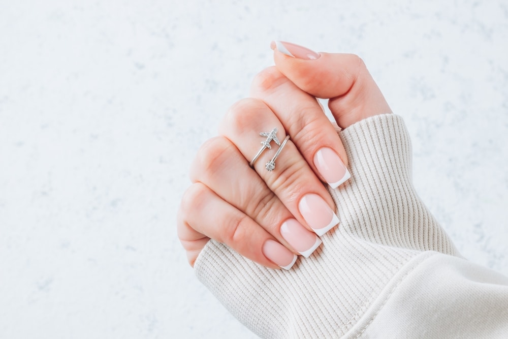 Female fingers with beautiful French manicure nails on white background.