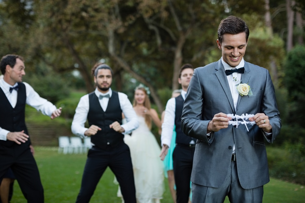 a groom wearing gray suit holding a wreath