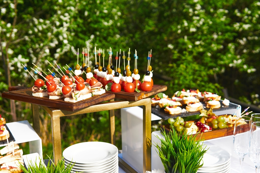 table with canapes on cocktail sticks against the background of flowering trees