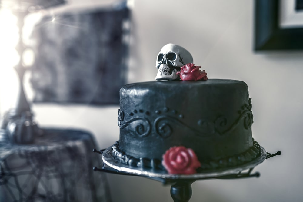 A Black Fondant Cake With A Skull Topper And Deep