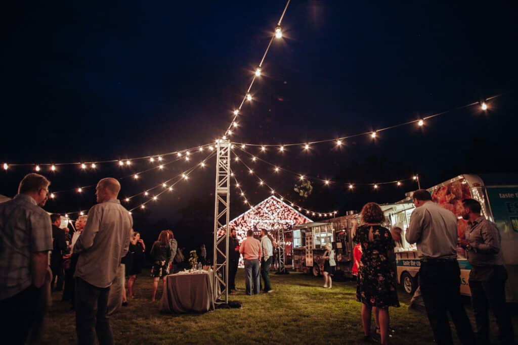 A view of a backyard food truck wedding at night with lighting