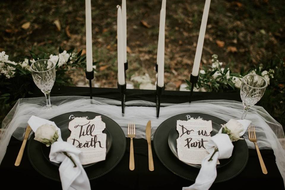 A view of a moodly dark table at a goth wedding with till death do us part written on papers in plates
