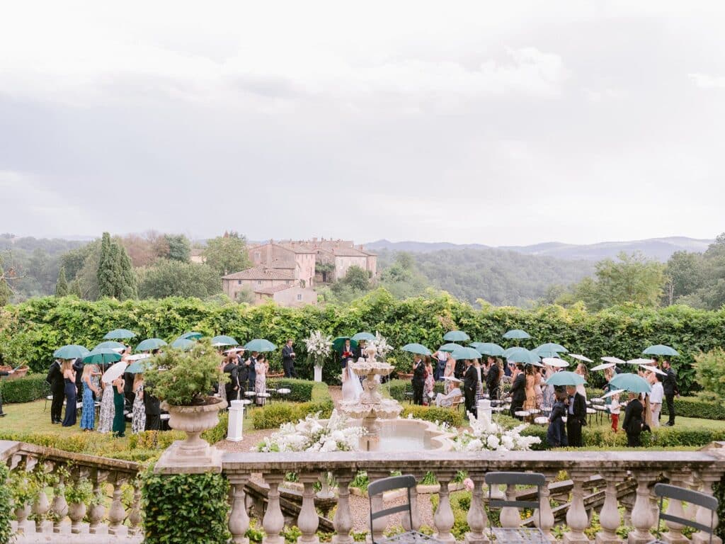 A view of people holding umbrellas at a scenic wedding