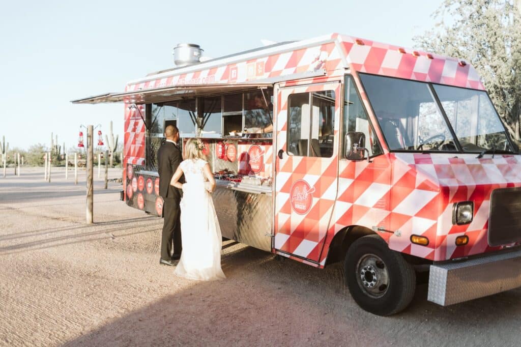 A wedding couple standing in front of a food truck ordering