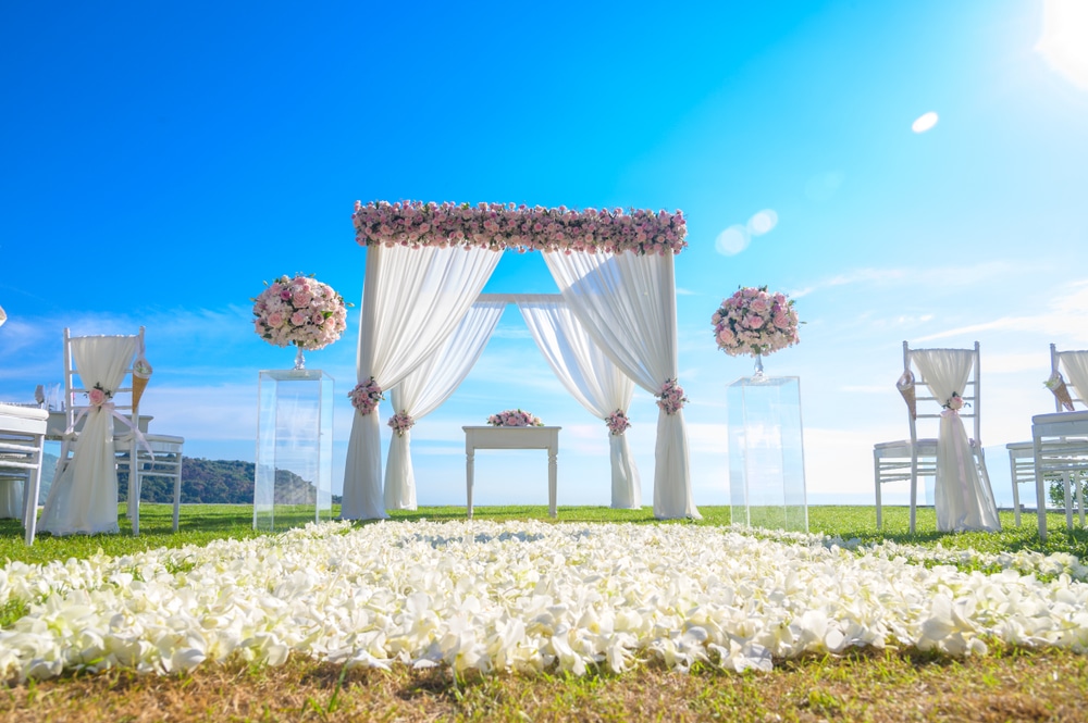 Arch decorated with flowers on the lawn beach background