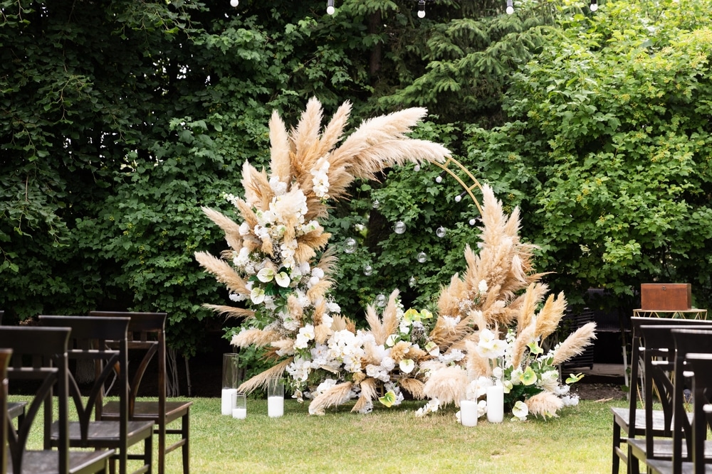 Beautiful Boho Wedding Arch With Green Plants And Wooden Chairs