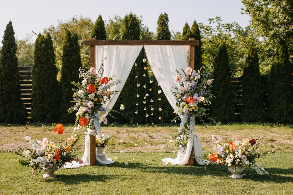 Floral draped wedding arch outdoors in sun light