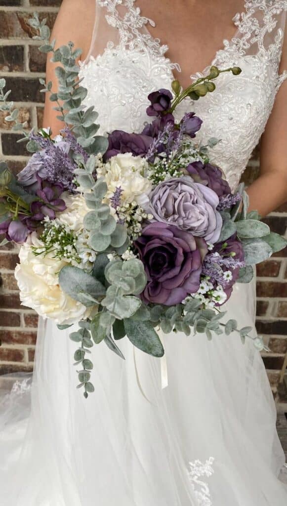 a bride is holding a bouquet with saga green color flowers and purple flowers