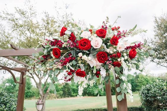 a decoration with saga green color flowers and red roses