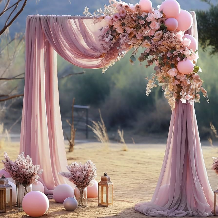 arch with draped fabric in pink color decorated with flowers set up in ground