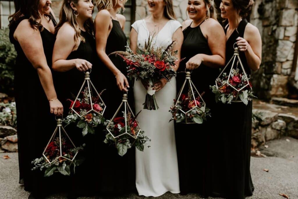 bride and bridesmaids in black gown carrying flowers https://www.weddingwire.com/wedding-ideas/halloween-themed-wedding-ideas Why a Halloween Wedding? You might be thinking why on earth would anyone go for a spooky wedding like this? But, wait, I am going to give you answers. It is because Halloween symbolizes undying love, quirkiness, a shift from the boring usual weddings, and much more. Here is a detailed answer to your why: 1: Halloween Wedding has a Unique Atmosphere The romance and mystery of the Halloween season combine to create a unique atmosphere that is perfect for a Halloween wedding. Any location can be transformed into a mystical wonderland with the help of Halloween wedding decorations, which will captivate guests as soon as they arrive. 2: Customized Design Couples can showcase their distinct personalities by planning a themed celebration that reflects their shared love of all things eerie and fantastical. The options for personalization are boundless, from adding themes from their favorite Halloween films to creating unique Halloween costumes for the bridal party. 3: Endless Creativity Options in Halloween Wedding With its unlimited possibilities for adjustment and creativity, the Halloween theme offers everything from gothic elegance to whimsical playfulness. When it comes to wedding decorations, couples can get creative and choose to use spiderweb table runners, black roses, or even a haunted dance floor. 4: Experience to Remember The excitement of attending a Halloween wedding will live on in the memories that guests will have for years to come. There’s more excitement and surprise in addition to the typical wedding activities like toasting and dancing. 5: Halloween Themed Wedding Welcomes Tradition with a Modern Spin Whether it’s through themed décor, black wedding clothes, or costume dress codes, couples can pay tribute to tradition while adding their own unique touch. While some people might find the idea of a Halloween wedding offensive, those who embrace it frequently discover that it is the ideal representation of their values and relationships. 6: Astounding Entertainment Halloween weddings give the opportunity to add unique entertainment choices such as scary photo booths, fire performers, or fortune tellers. Couples can surprise and please their guests with unexpected twists and performances in addition to the standard wedding entertainment. 7: Temporal Charm The festivities are made more beautiful by the autumnal backdrop, which is enhanced by the crisp air and vibrant leaves that contribute to the enchanted atmosphere. The season has practical advantages as well, such as milder temperatures and fewer scheduling conflicts, in addition to its visual appeal. Halloween-themed Wedding Ideas: Unusual Twist Hello folks, we are here with a bucket of vintage Halloween wedding ideas that will transform your big day into something truly magical. So, without wasting time, let’s discuss the ideas. bride and groom at a haunted venue holding pumpkins and dressed up https://www.weddingwire.com/wedding-ideas/halloween-themed-wedding-ideas 1: Opt for a Haunted Venue A spooky pick for your haunted venue can be spotted among the whispering October winds: a shadowy house, a historical castle, or a historic theater echoing with ghosts of the past. These creepy locations are the ideal backdrop for your Halloween-themed wedding, drawing guests into a world where mystery and magic exist. Halloween wedding ideas come to life with ghostly visions dancing over the walls, candlelight pathways leading to forgotten places, and spider webs adorning towering chandeliers. But beyond the eerie charm, these places also have a useful appeal. Additionally, these venues provide enough space for the ceremony and reception, enhancing the magical ambiance of your wedding day. In addition, a haunted venue’s rich history and atmosphere give your celebration a greater sense of meaning and help you make memories that will last long after October 31st hits midnight. gothic wedding invitaions in black white and golden https://margoandbees.com/p/7/407/18249/wedding_invitations_gold_/_rose_gold_/_silver_/_glitter_01/velgpxbmoon/z.html 2: Choose Gothic Invitations for the Halloween Wedding An invitation appears in the murk of whispering moonlight, drawing guests to the gothic world of a Halloween wedding, where romance and gloom meet. The invitation is the first step in ideas for a Halloween wedding, defining the mood for such a hauntingly lovely celebration. Select from mesmerizing patterns influenced by well-known horror stories, such as the spooky elegance of The Nightmare Before Christmas, or embrace gothic elements like blood-red roses and intricate lace. The invitation, however, is the bride and groom’s vision; it reflects their selected color palette and sets the tone for a party unlike any other, even though the themes may differ. Gothic invites not only set up the tone but also give a sophisticated touch to the wedding ceremony, making sure that every element has a sinister charm. bride and groom wearing halloween inspired wedding attires https://www.weddingomania.com/31-striking-halloween-wedding-dresses/ 3: Wedding Dresses Inspired by Halloween Theme Guests flock to a Halloween wedding like ghosts to a spooky tune under the eerie brightness of the lunar night. The celebration is made even more magical by the costume dress code, which invites everyone to express their inner whimsy and dress up as characters of their choice. There are countless options for creative Halloween wedding costume ideas from classic monsters to mythical creatures. But while some could go all out for Halloween wedding costumes, others might prefer more understated parallels to the theme, such as chic clothing with eerie accents. There are several alternatives available for the bride, ranging from a dramatic black gown that perfectly captures the essence of the night to a classic wedding dress with Gothic-inspired accents. In addition, the groom’s clothes might vary from a classic suit with a mysterious touch to elaborate couple costumes that showcase their common interests. Regarding the guests, there is no limit to their creativity when they are invited to wear a Halloween wedding guest dress. Apart from traditional wedding wear, attendees will find a range of costume ideas, varying from playful to eerie. Even though some people might be afraid to dress in character, the dress code urges guests to have a spirit of curiosity and companionship. Additionally, it guarantees that everyone gets lost in the occasion’s enchanting ambiance. The costume dress code gives a special touch to the wedding ceremony, turning it into a celebration unlike any other. It can range from spooky elegance to whimsical playfulness. In addition to increasing the visual extravaganza, it inspires guests to fully embrace the spirit of the occasion and make lifelong memories. Besides, the dress code gives couples a chance to pick out every part of the occasion, allowing it to represent their shared love of all things eerie and fantastical. pumpkin weddding decor with colorful flowers https://whimsicalwonderlandweddings.com/pumpkin-wedding-ideas/ 4: Pumpkin Décor Perfect for Halloween Wedding Amidst the eerie murmurs of the night, there is a captivating story interwoven with the enigmatic charm of the season and the flickering light of candles. When it comes to Halloween weddings, one décor element rules and fascinates everyone, it comes close to the pumpkin. Celebrating the spirit of a Halloween-themed wedding, pumpkins provide an enchanting blank canvas for personalization and creativity. But it’s not just any pumpkin that adorns these dimly lit hallways; the ethereal glow of white pumpkins adds an unearthly sophistication to the event. Furthermore, these gourds take on symbolic meanings of love and harmony when they are embellished with elaborate carvings, lace-like designs, or delicate blossoms. White pumpkins are visually appealing as well as symbolic of purity and fresh starts, which makes them ideal for the holy bond of marriage. bride in white gown holding a halloween inspired bouquet https://www.lingsmoment.com/blogs/news/spellbinding-halloween-wedding-ideas 5: Bridal Bouquet Inspired by Halloween Theme The bridal bouquet appears under the gloomy Halloween moonlight, as a bewitching fusion of splendor and gloom. It reflects the mystery of the season with its black calla lilies, spiderweb lace, and blood-red roses. Despite being unusual, this bouquet perfectly fits the theme and adds a gothic elegance to the wedding ceremony. It also acts as a symbolic addition, linking the bride’s outfit to the day’s themes. In addition to being visually appealing, it becomes a stunning highlight of the wedding with simplicity. It also allows for personalization with little pumpkins or black feathers, which goes well with a variety of wedding Halloween costumes. Coordinating with the bride’s accessories or wedding nails enhances every aspect of the design. In the end, the Halloween bridal bouquet turns the wedding into a fanciful, bewitching celebration of love. candlelit wedding ceremony in a hall https://www.worldsbestweddingphotos.com/35-candlelight-ideas-romantic-weddings 6: Candlelit Wedding Ceremony With a lighted ceremony, it’s time to enter the dreamy world of a Halloween wedding where suspense and dancing shadows reign. With a trail of softly lit lights, the atmosphere is reminiscent of gothic elegance and magic. Lanterns, ethereal orbs, and antique candelabras add even more ambiance. With their diverse designs, candles come in black or scented varieties in addition to conventional tapers. They represent warmth and the insatiable flame of love along with attractiveness. The outcome is an engaging and personal encounter, even though practical concerns like venue laws and safety are important. In the middle of the Halloween celebration’s splendor, a candlelit ceremony adds a romantic touch, highlighting important details and producing moments that will never be forgotten. variety of spooky cocktails in variety of glasses https://www.hgtv.com/lifestyle/entertaining/scary-good-halloween-cocktails-pictures 7: Offer Spooky Cocktails for Your Halloween Wedding Imagine your Halloween wedding guests being enticed by an appealing variety of eerie cocktails amid the flickering candles and spooky whispers of the night. These drinks are a great way to start a conversation while also giving the party a dark touch. Wedding-related Halloween decorations can be simply integrated into the cocktail display. It can be done with bubbling dry ice cauldrons topped with edible glitter and gummy worm garnishes. The drink menu, which includes selections like “Blood Orange Margaritas” and “Witch’s Brew Punch,” is expertly made to capture the spirit of the season. It also presents a chance to highlight creativity. In addition to having eerie titles, these cocktails can be made in line with the wedding’s color palette, giving the wedding day even more thematic coherence. These cocktails, despite their classic presentation, have a humorous touch that highlights the whimsical mood of a Halloween wedding. dark floral decor with a skull placed as a decorative item on the table forks and some spoons with candles https://www.pinterest.com/pin/20-unique-decor-ideas-for-a-halloween-wedding--52495151896335408/ 8: Dramatic Dark Florals for Décor Deep in the night, amongst murmurs of darkness and moonlit mysteries, blossoms with a deeper charm are waiting to add an unsettling elegance to your Halloween-themed wedding. Bask in the charm of strikingly black flower arrangements, as Halloween-themed wedding inspiration unfolds into captivating elegance. Enter a paradise of choices, where deep crimson roses express passion and desire and black calla lilies exude mystery and sophistication. Despite being out of the ordinary, these flowers give your event a mysterious and dramatic feel while enticing attendees with their eerie charm. In order to create a hauntingly lovely bouquet appropriate for a gothic romance, you should also entwine thorny branches and dark foliage for extra texture and depth. But the story the flowers tell, one that masterfully combines the themes of love and darkness, is what really makes them stand out as an exquisite demonstration of nature’s artistic ability. Furthermore, these flowers do more than just add a decorative element to your Halloween wedding; they become an essential component, adding a touch of ethereal magic to every moment. halloween themed cake with skulls on it https://www.pinterest.com/pin/cafemomcom-skull-halloween-wedding-cake-15-halloween-wedding-cakes-for-creepy-coupl--309200330676385586/ 9: Halloween Themed Gothic Cake A Halloween wedding cake that radiates an ominous elegance emerges from the shadows of dark passageways where whispers linger and darkness dances. This masterwork of desserts captures the spirit of the event by fusing extravagance with the eerie charm of the time of year. But underneath its gloomy façade is a symphony of flavors just waiting to entice the senses. Couples can also select from a variety of enticing selections, like midnight black forest, ominous chocolate orange, or blood-red velvet. Even while every flavor evokes a distinct charm of its own, they all blend in perfectly with the event’s aura of mystery. Furthermore, these Halloween wedding cakes turn into magnificent pieces of art when adorned with intricate lace designs, swirls of frosting, and maybe even a dash of edible metallic accents. In addition, the final touch of spooky cake toppers like tiny gravestones, skeleton hands, or masquerade masks gives the event an unsettling yet lovely touch. collage of ghostly photobooths https://fixthephoto.com/halloween-photo-booth-ideas.html 10: Ghostly Photo Booth Nestled in the shadowy nooks and crannies of your Halloween wedding location is a spooky sight that is sure to capture your guests’ attention: the Ghostly Photo Booth. With its eerie charm, this ghostly nook asks guests to keep their ghastly smiles and ghostly grins for all time. This isn’t just any photo booth, though; it’s an entrance to the otherworldly, where each picture turns into a timeless, spectral image. In addition, when creating this dreamy work of art, imagine a background of frayed curtains covered in spiderwebs and lit by flickering candles. In order to further enhance the eerie atmosphere, add objects like old lights, ghostly veils, and antique frames. While it might appear like a fanciful addition, the photo booth actually blends in perfectly with the wedding ceremony, providing guests with a brief yet fun break from the somber elegance of the event. On top of that, to add even more spookiness, place tall Halloween wedding centerpieces around the booth. These centerpieces should include black roses, twisted branches, and flickering candles that create dark shadows around the space. a woman tying corsage on other womans wrist https://www.lingsmoment.com/products/wrist-corsages-in-twilight-purple-harvest-orange 11: Corsages for Guests As guests arrive at the eerie Halloween wedding location in the soft light of dusk, they encounter an enigmatic charm: the enticing corsages adorning their clothing. In the midst of a spooky atmosphere, beautifully designed flower decorations known as corsages bring a magical touch to the event and symbolize elegance. Furthermore, corsages are not only ornamental but also act as thank-you gifts for visitors, recognizing their presence on this enchanting day. Typically worn by women, corsages can be tailored to fit any type of guest, male or female. To add a gothic touch, though, consider using unusual materials for your Halloween wedding, such as dark feathers, deep purple orchids, or black roses. Additionally, add themed components to the corsages, such as small bats, spiderwebs, or miniature pumpkins, in addition to standard floral patterns. These unusual selections give a subtle yet eye-catching touch to the wedding ceremony, perfectly blending in with the Halloween theme. cemetery inspired seating chart with transparent chairs and a black fabric draped table https://www.friartux.com/blog/post/halloween-inspired-wedding-at-a-cemetery 12: Cemetery Seating Arrangement for Halloween Wedding Imagine a hauntingly beautiful sight in the hazy veil of dusk: a Cemetery Seating Chart for your Halloween wedding. Gravestones with ghostly grace point guests to their final resting places here. This ghastly but unusual accent gives your party a special appeal. With witty epitaphs or the names of beloved family members who have passed away, each gravestone serves as an accessory and escort card. But rather than being made of chilly stone, these markers can be made of wood, foam, or even paper and decorated with fake cobwebs, moss, and spooky lighting. Additionally, this option offers a memorable twist on traditional seating arrangements and is in great harmony with the theme. halloween inspired wedding favors in small jars https://www.micoope.com.gt/?o=48-awesome-halloween-wedding-favors-weddingomania-nn-0bEd21T2 13: Themed Favors for Halloween Wedding You have the chance to give your guests dreaded souvenirs of your unwavering love in the shadowy corners of your Halloween wedding. With themed treats that linger in the minds long after the festivities end, embrace the festive mood. Think about eerie treats like candy-filled small potion bottles, customized magic books, or candles with a pumpkin fragrance. Despite their unusual appearance, these favors go wonderfully with the magical atmosphere of your party. In addition, these kinds of presents double as keepsakes of your memorable day, reminding guests of the enchantment they felt among whispered vows and flickering candlelight. escort cards with skull prints https://www.etsy.com/listing/907665450/till-death-do-us-part-place-cards-skull 14: Skeleton Escort Cards Skeletal key escort cards lead guests to their ethereal destinations as they encounter an unsettling touch in the soft glow of candles Although frightening at first glance, these keys might potentially unleash priceless moments during a Halloween wedding. A scary memento, each key bears the names and table numbers of the attendees. In addition, couples can add personal touches by sticking charms or tiny mementos to the keys, which will symbolize their individual love tale. Apart from fulfilling a practical duty, these escort cards offer the ceremony a hint of gothic elegance, bringing it together perfectly with the magical atmosphere of the occasion. mid night send offs at a halloween themed wedding bride and groom kissing guests carrying sparkling candles https://bigskyphoto.com/2022/08/wedding-sendoffs-or-exits/ 15: Mid-Night Send Offs The Halloween wedding ends with a hauntingly gorgeous Midnight Send-Off beneath the moon’s spooky radiance over the magical location. The attendees receive escort cards resembling little gravestones with their names engraved in a gothic script. These aren’t your typical cards, though; within each one is a tiny LED light that brightens the path to their final resting spot. Additionally, the gravestones are customized with mystical symbols, bats, or spiders to further enhance the mood of the event. These special escort cards not only show guests where to sit but also act as keepsakes of a marriage between two souls amid the spookiness of Halloween. You can also check out other spooky ideas for Halloween themed weddings in this article. Conclusion Wrapping up, the article covered 15 captivating ideas for Halloween-themed wedding ceremonies. With these spooky and ghouling ideas, you can transform your big day into a magical evening. So, try out these ideas now and enjoy the spectacular day. Spooky Inspirations!