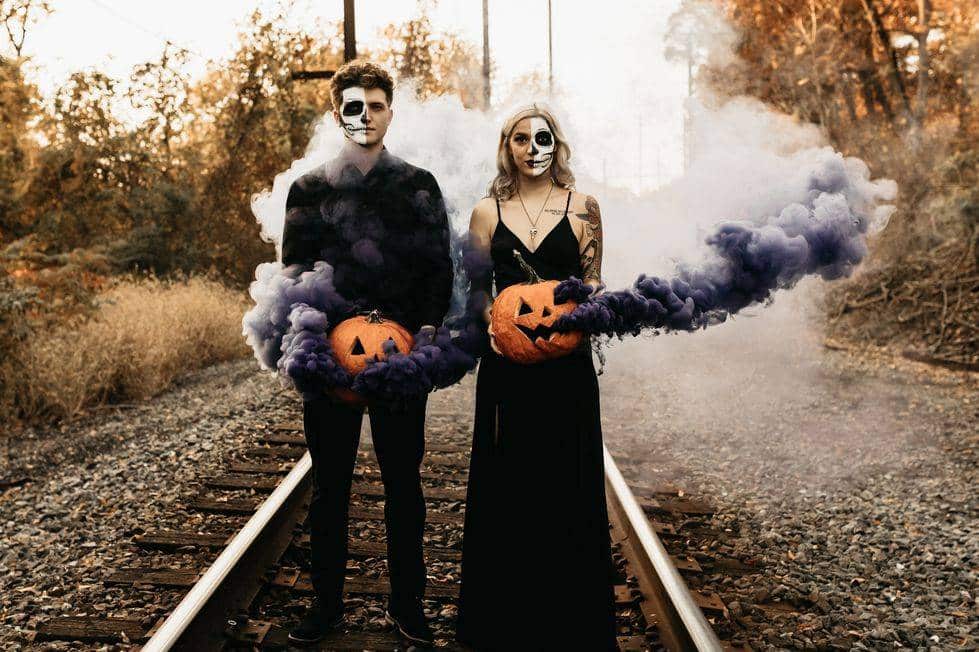 bride and groom at a haunted venue holding pumpkins and dressed up