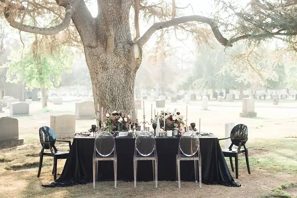 cemetery inspired seating chart with transparent chairs and a black fabric draped table