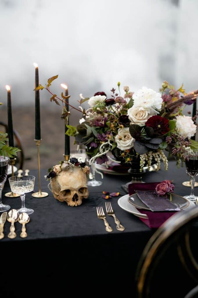 dark floral decor with a skull placed as a decorative item on the table forks and some spoons with candles
