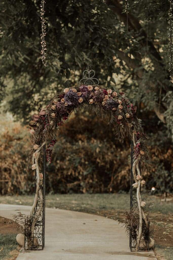 gothic wedding arch with rustic and dark colored decorations with rustic flowers