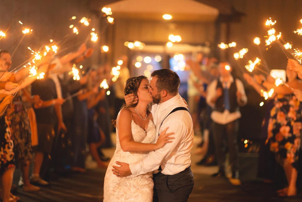 mid night send offs at a halloween themed wedding bride and groom kissing guests carrying sparkling candles