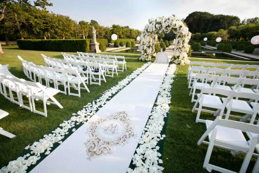 monogram aisle runner with whiote flower adorned on the side white chairs