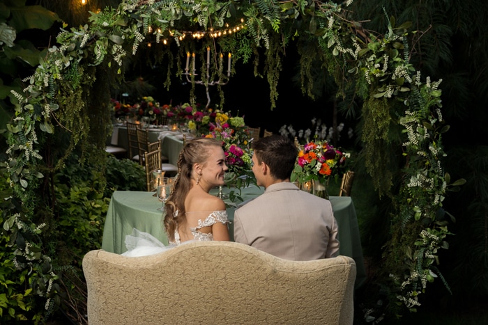 secret setting in a garden for wedding a bride and groom sitting and talking on the sofa