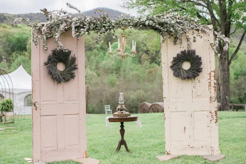 vintage inspried wedding arch deocrated with rustic leaves setup in a ground