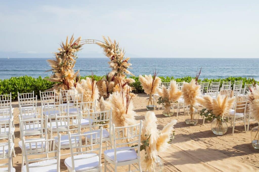 wedding aisle and arch set up along waters white chairs and bushy decor