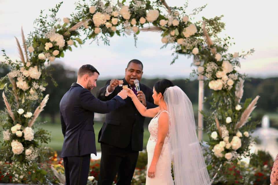 A couple cheering with the father at a unitarian traditional wedding