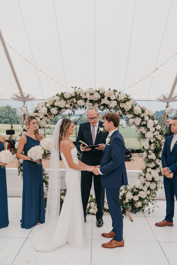 A view of a couple taking vows with a father and thier best man and bridesmaid