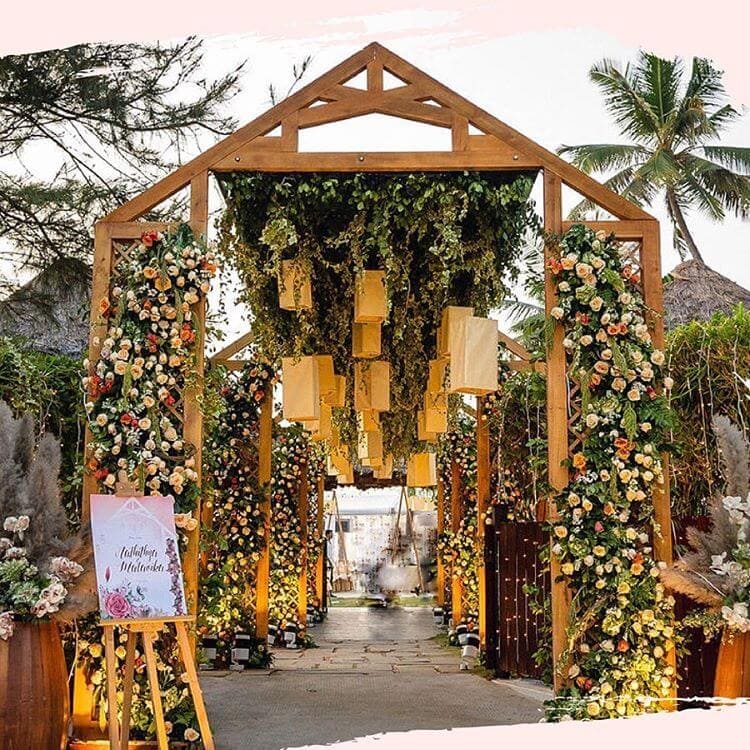 A view of a floral grand entrance of a wedding with a wooden frame