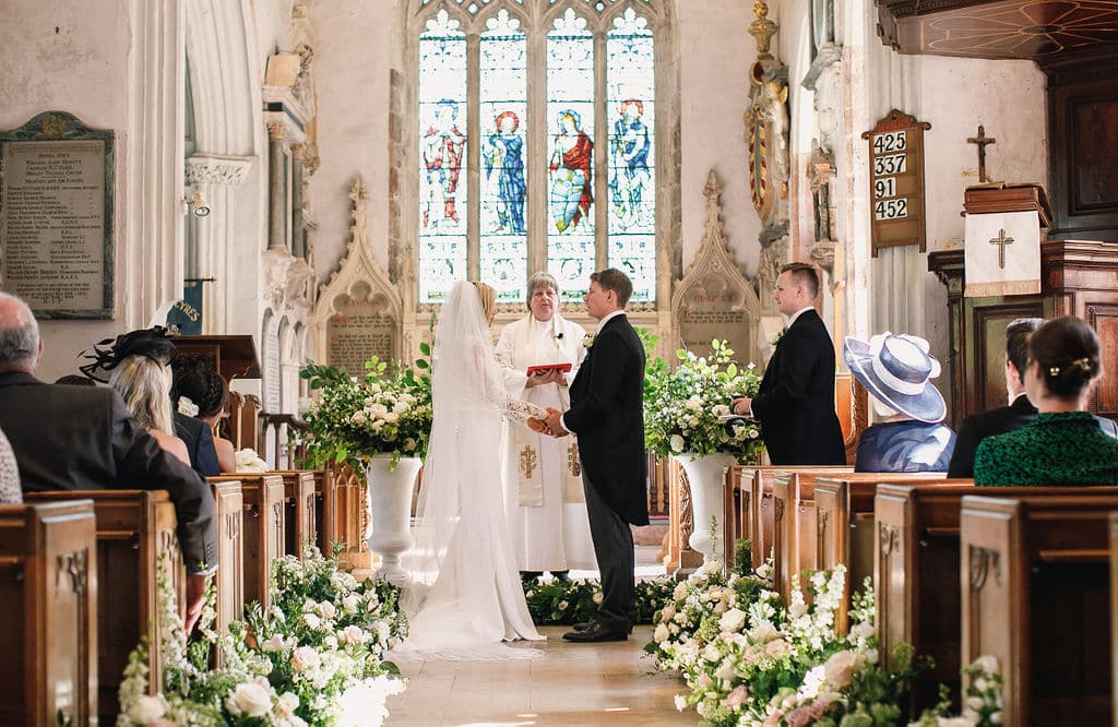 A view of bride and groom taking vows in a church with people and priest