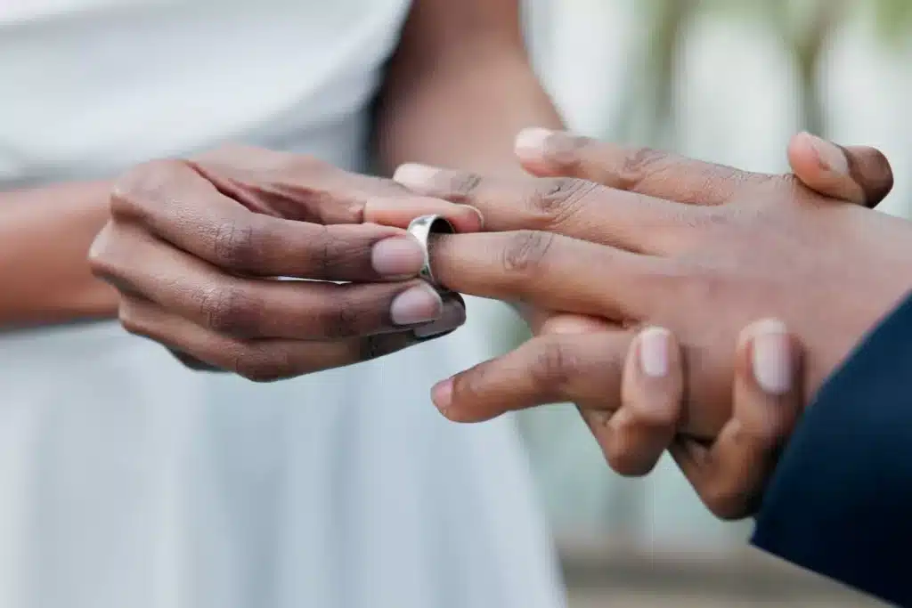 A view of hands of two people exchanging rings for marriage