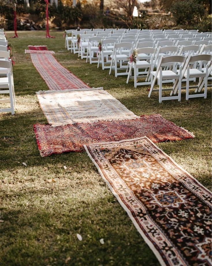 A view of vintage rug placed on grass in an outdoor wedding setup