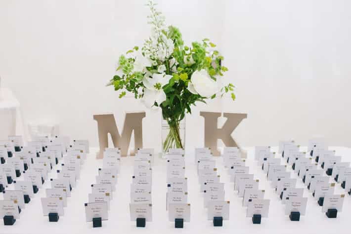 A view of wedding escort cards placed along with flowers and initials of bride and groom