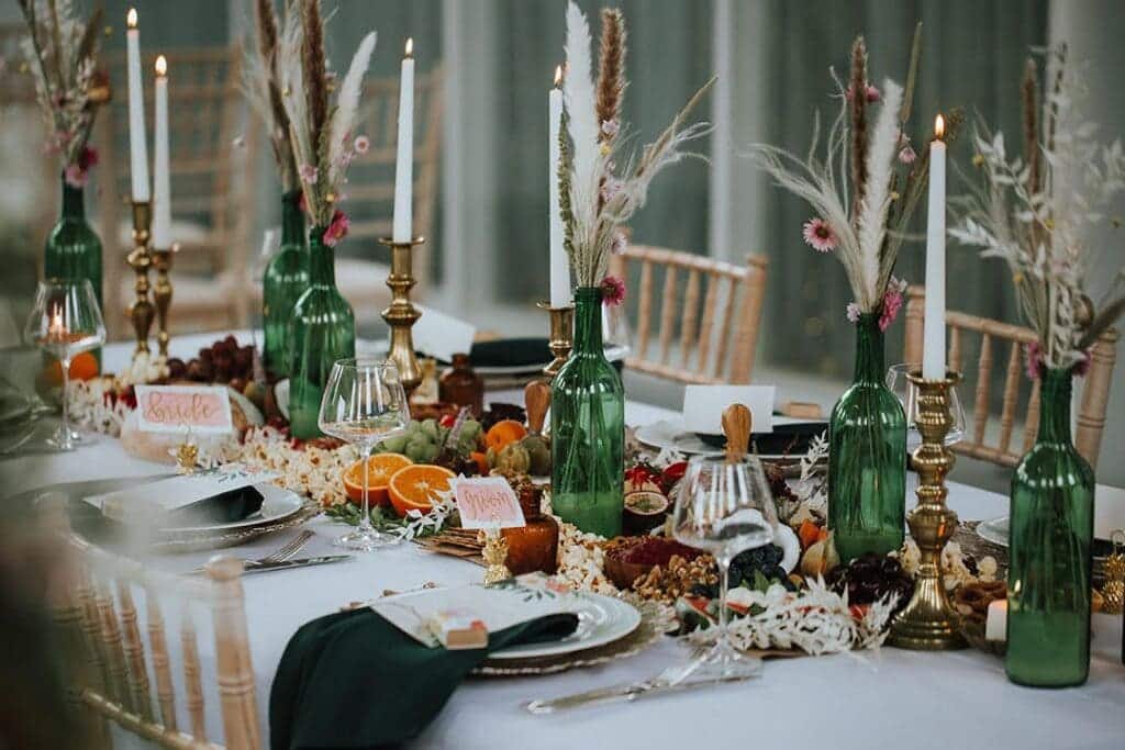 A view of wine bottles on a wedding table with flower decor in them