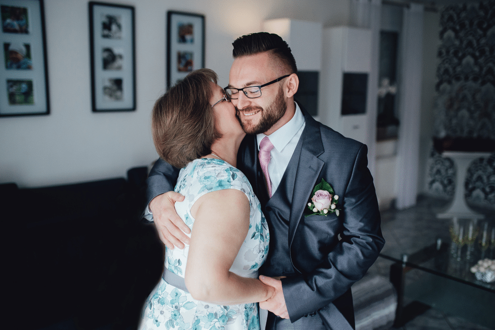 Portrait of a handsome groom in a grey suit with a tie with his mother