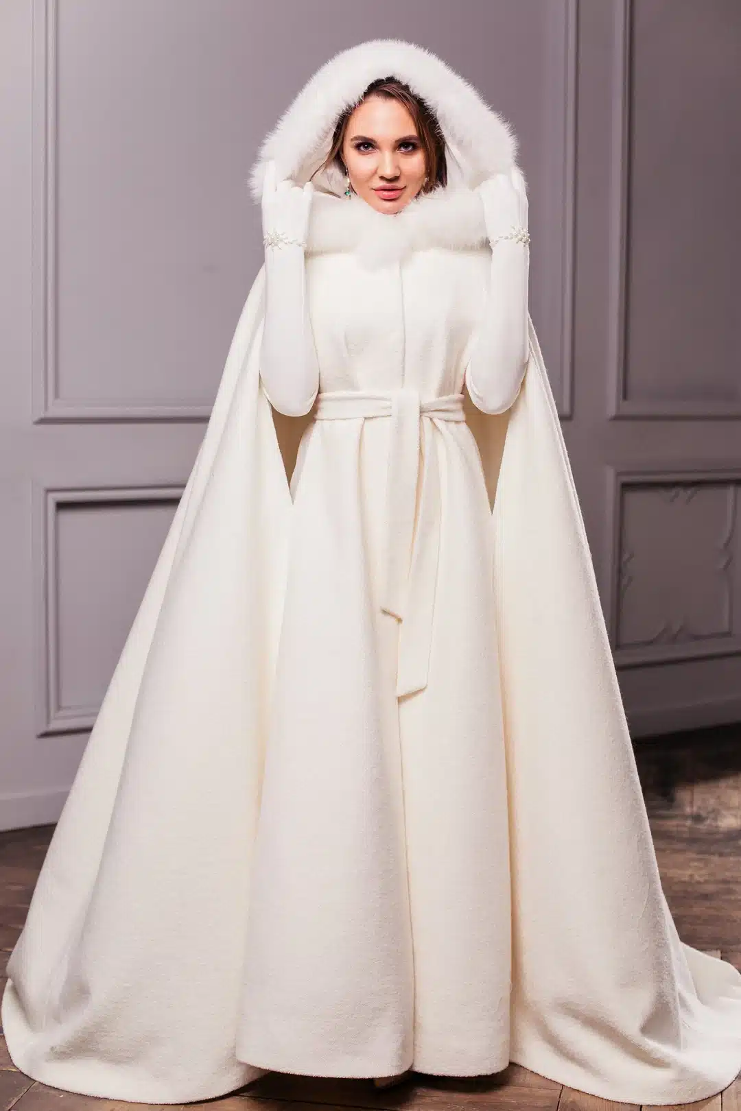 a bride wearing long white dress along with the fur cape jacket