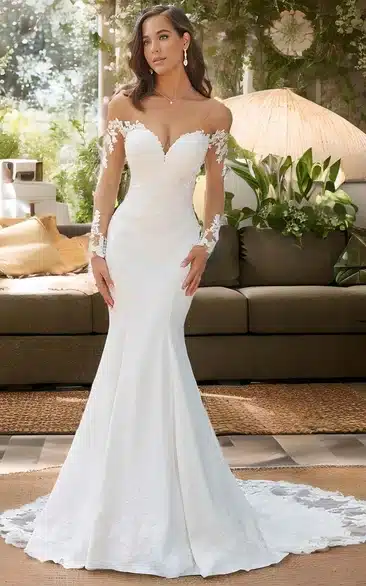 a bride wearing the long white marmaid gown with off shoulder full sleves