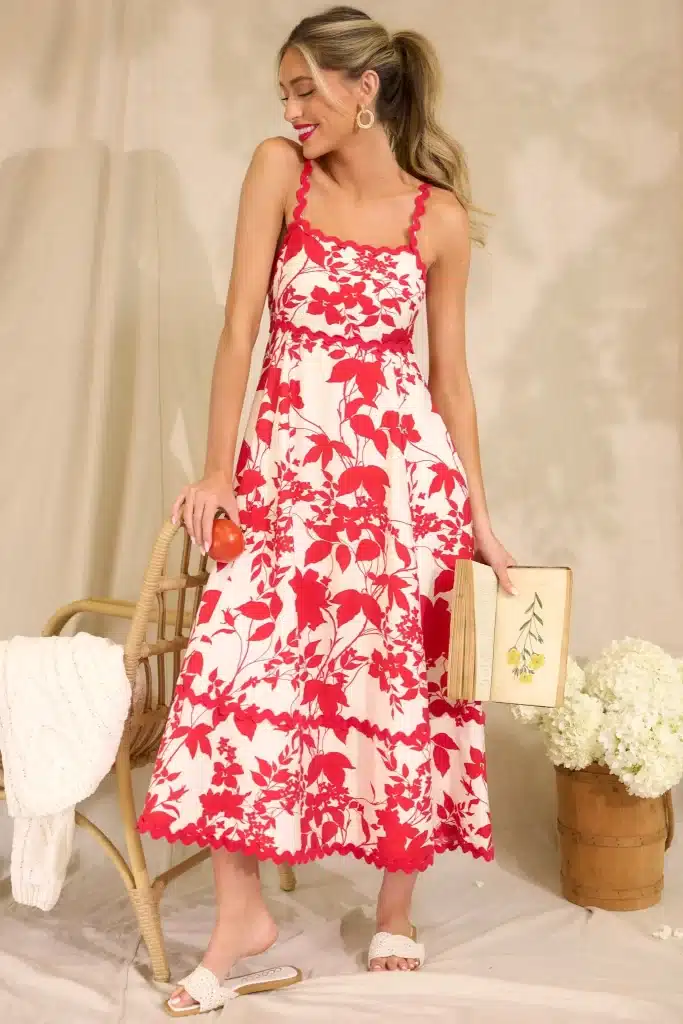 a girl wearing the red floral dress holding a book in her hand 