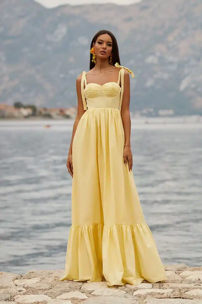 a women wearing yellow color ruffle dress standing on a beach