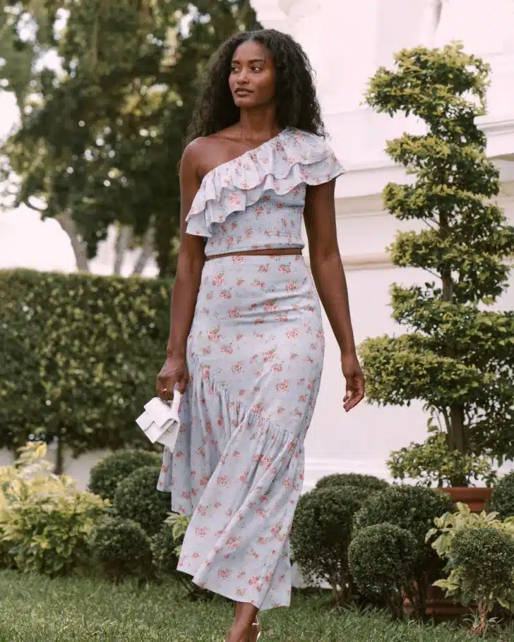 a women wearing one shoulder dress along with having a mini white bag in her hand