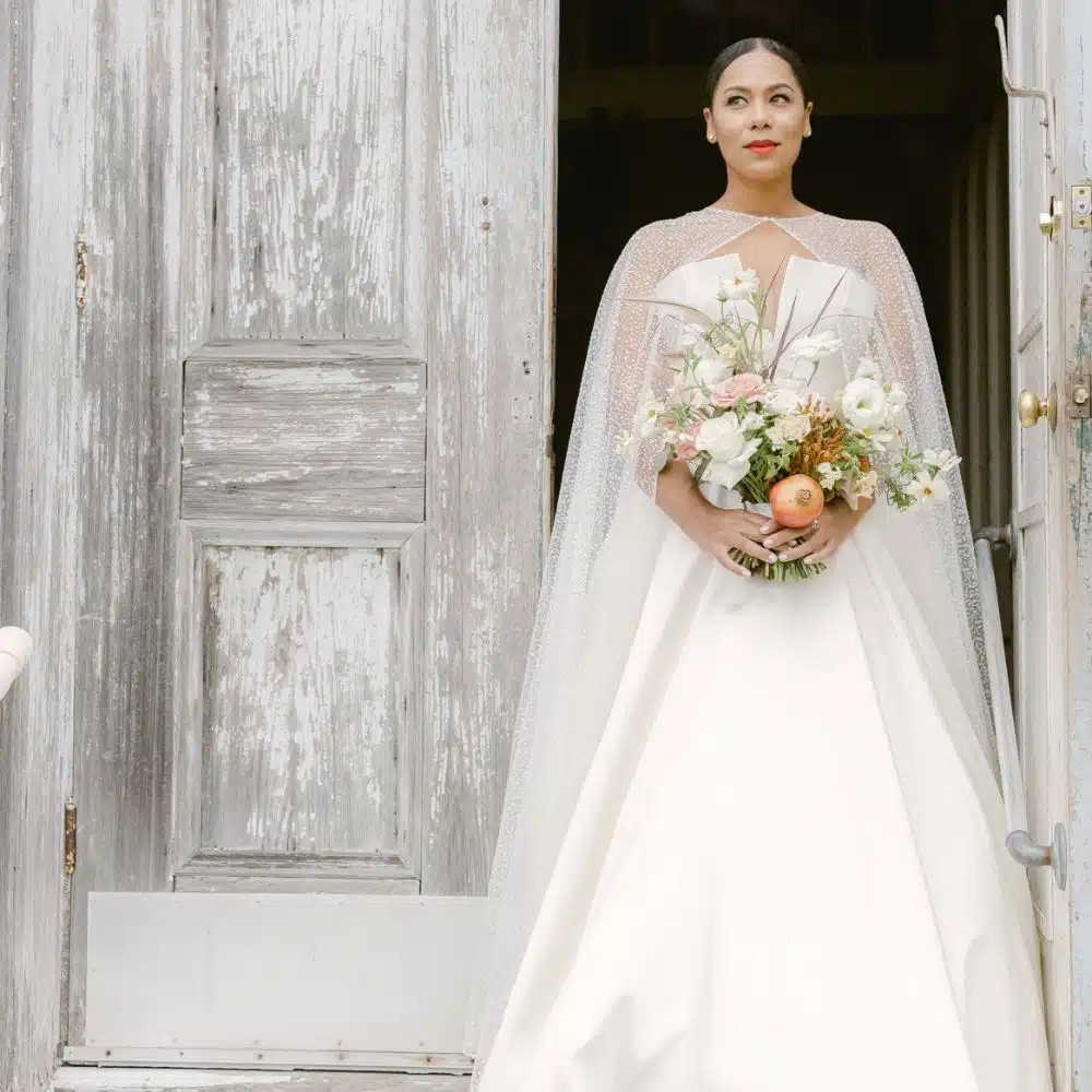 bride is wearing the cap wedding gown along with the flowers in her hands