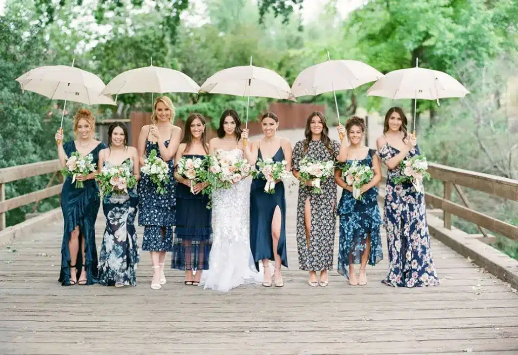 bridemaids waering blue floral dresses and holding umbrellas