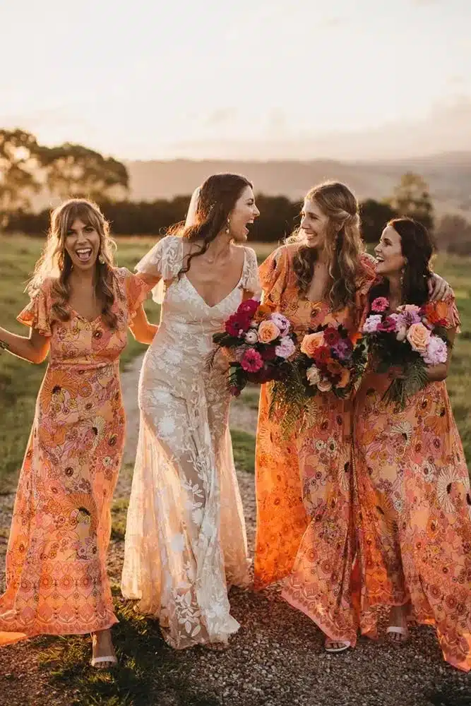 bridemaids wearing orange floral dress and holding flowers