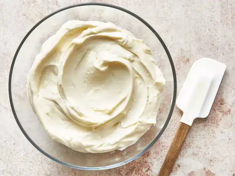 a bowl of cream cheese frosting and a spatula