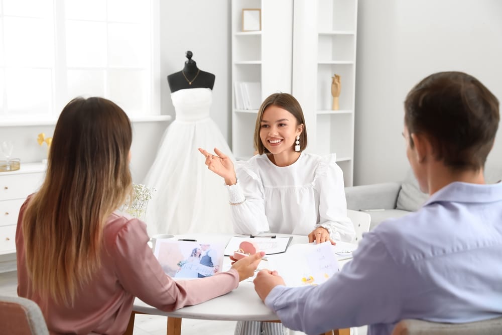 Female Wedding Planner Discussing Ceremony With Clients In Office